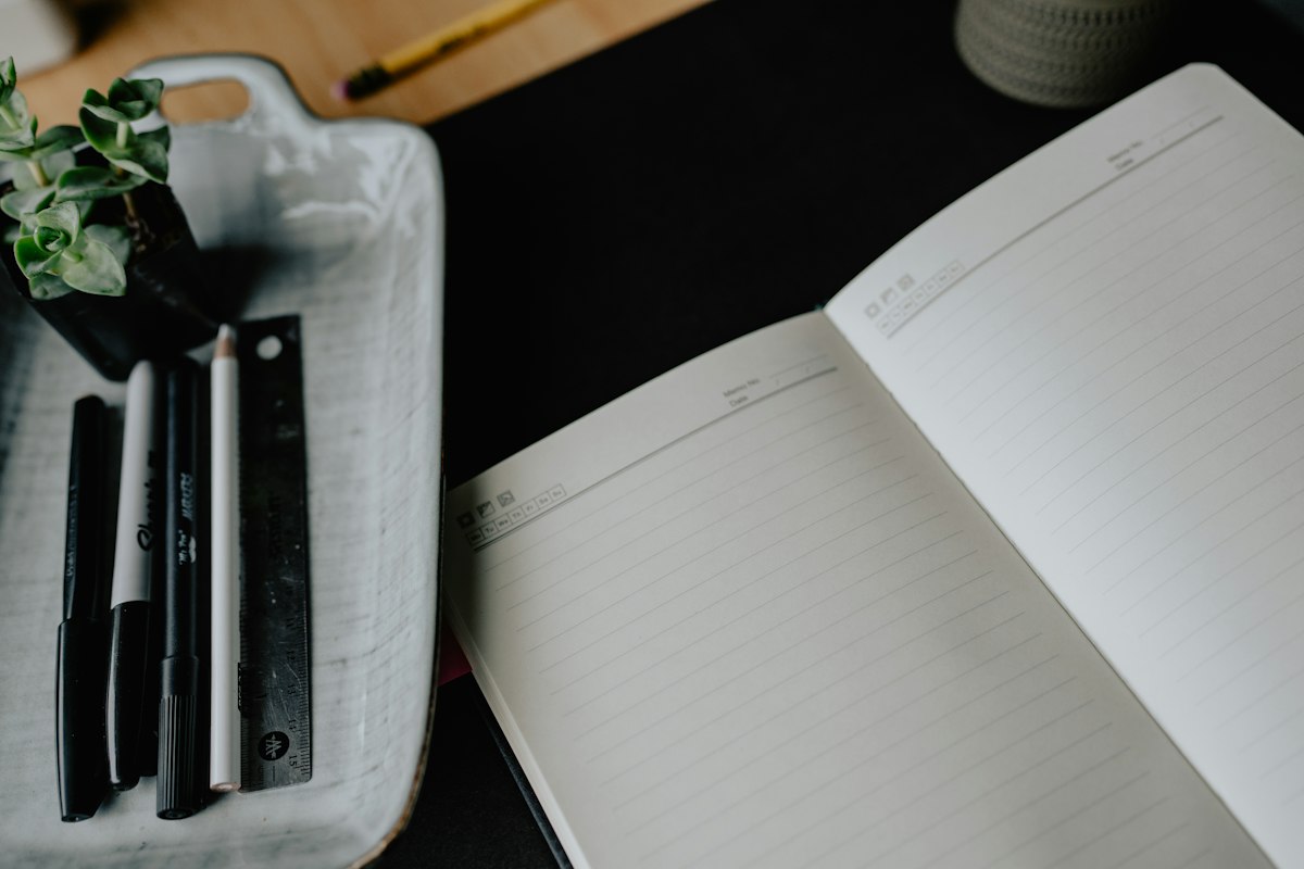 Cuaderno abierto con útiles de escritura sobre una mesa.